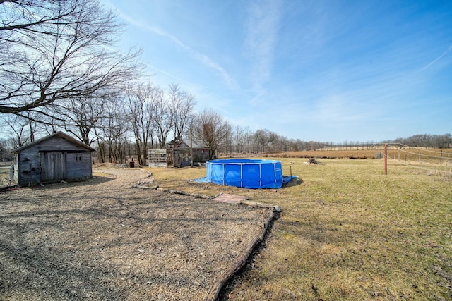 view of yard featuring an outdoor structure, an outdoor pool, and a shed