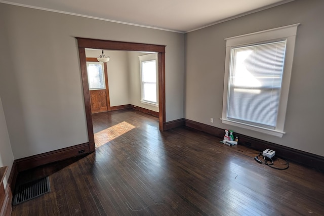 spare room featuring dark wood finished floors, visible vents, baseboards, and ornamental molding