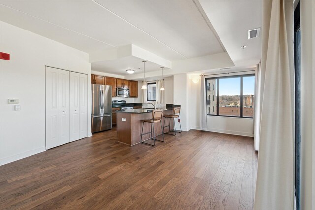 111 N Ashley St Unit 510, Ann Arbor, MI 48104 - kitchen featuring a peninsula, a tray ceiling, dark wood-type flooring, appliances with stainless steel finishes, and dark countertops