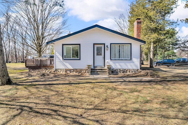 bungalow-style house featuring a wooden deck, a front yard, and a chimney