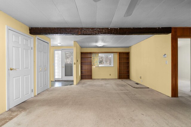 unfurnished living room featuring beam ceiling and carpet