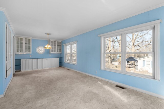 unfurnished dining area with light carpet, visible vents, crown molding, and baseboards