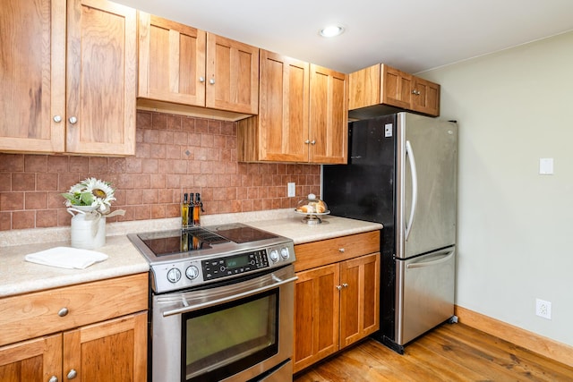 kitchen featuring decorative backsplash, stainless steel appliances, light countertops, and light wood-style floors