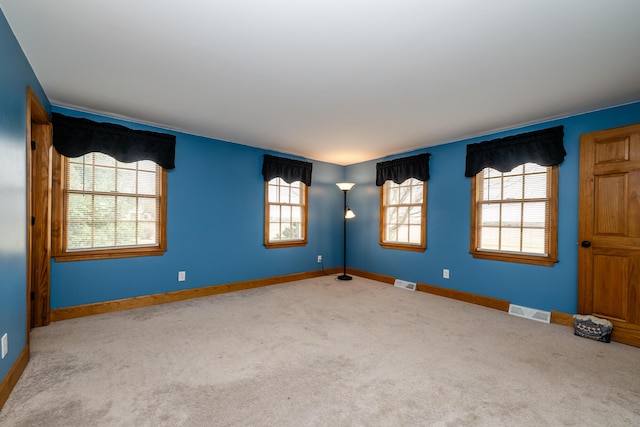 carpeted spare room with visible vents and baseboards