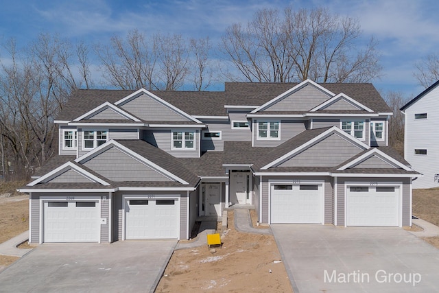view of front of house with concrete driveway, an attached garage, and a shingled roof