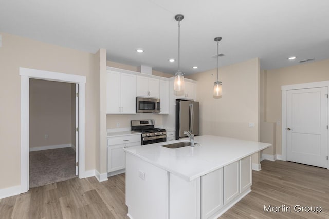 kitchen featuring visible vents, an island with sink, a sink, appliances with stainless steel finishes, and white cabinetry