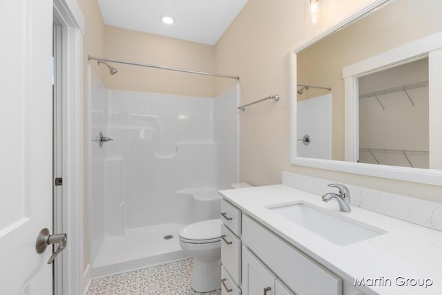 bathroom featuring toilet, vanity, and a shower