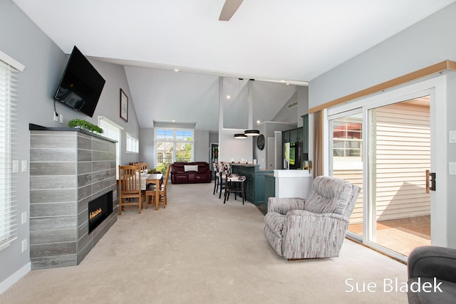 6735 Windflower Way, Norton Shores, MI 49444 - living area with a lit fireplace, light colored carpet, vaulted ceiling, and a ceiling fan