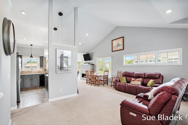 6735 Windflower Way, Norton Shores, MI 49444 - living area with high vaulted ceiling, light colored carpet, a warm lit fireplace, and recessed lighting