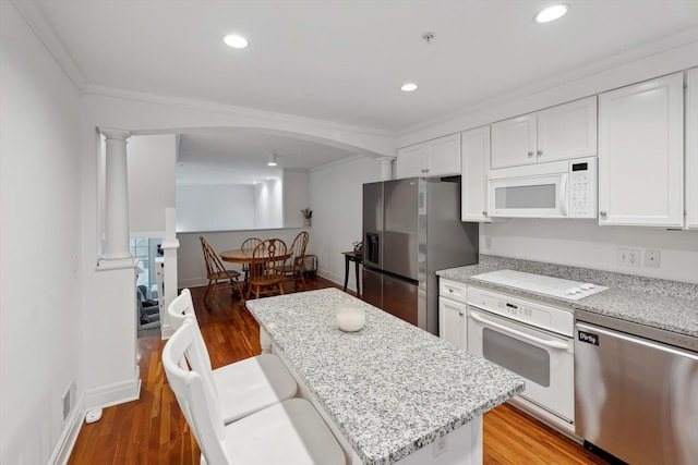 kitchen with light wood finished floors, ornate columns, arched walkways, and stainless steel appliances