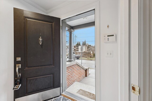 entryway with ornamental molding and decorative columns