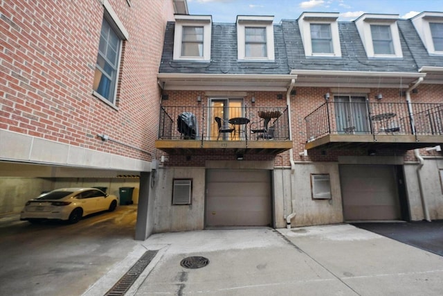 exterior space featuring brick siding, a balcony, and roof with shingles