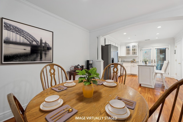 dining space with light wood-style floors, baseboards, arched walkways, ornamental molding, and recessed lighting