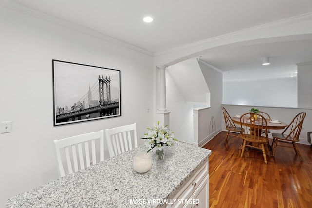 dining space with decorative columns, crown molding, wood finished floors, baseboards, and arched walkways