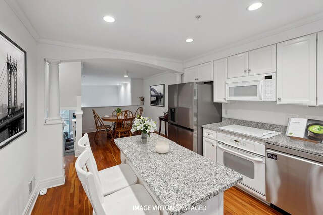 kitchen with ornate columns, arched walkways, ornamental molding, and stainless steel appliances