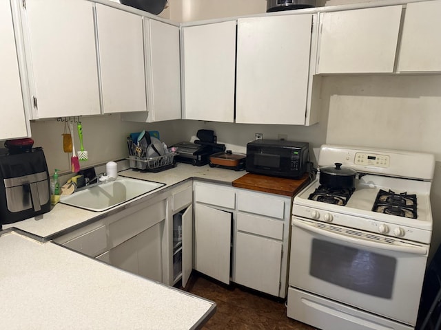 kitchen with a sink, white gas stove, black microwave, and white cabinets