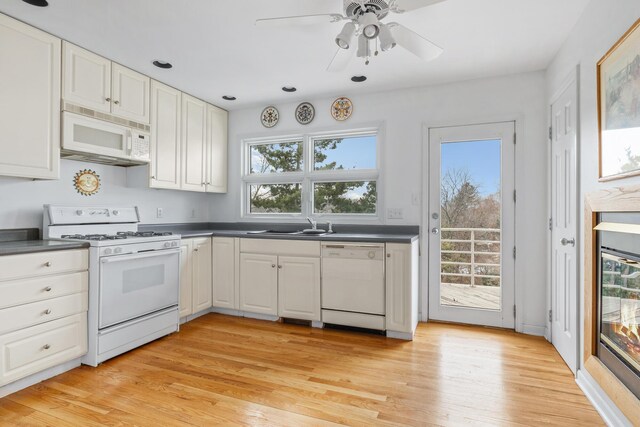 2019 Silvertip Ln, Long Beach, IN 46360 - kitchen with dark countertops, white appliances, white cabinetry, and light wood-style floors
