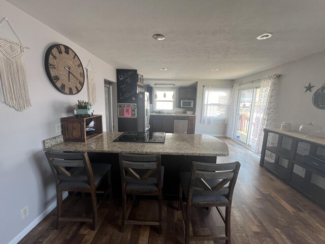 2772 S Wisner Ave, Fremont, MI 49412 - kitchen featuring light stone counters, dark wood-style floors, stainless steel appliances, a peninsula, and baseboards