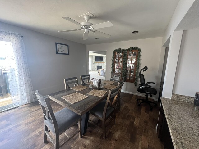 2772 S Wisner Ave, Fremont, MI 49412 - dining space with visible vents, baseboards, ceiling fan, a stone fireplace, and dark wood-style floors