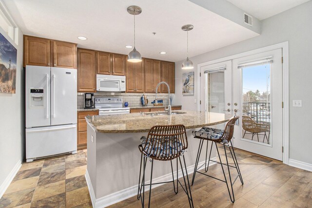 401 W Ludington Ave Unit 208, Ludington, MI 49431 - kitchen featuring visible vents, backsplash, french doors, white appliances, and a kitchen island with sink
