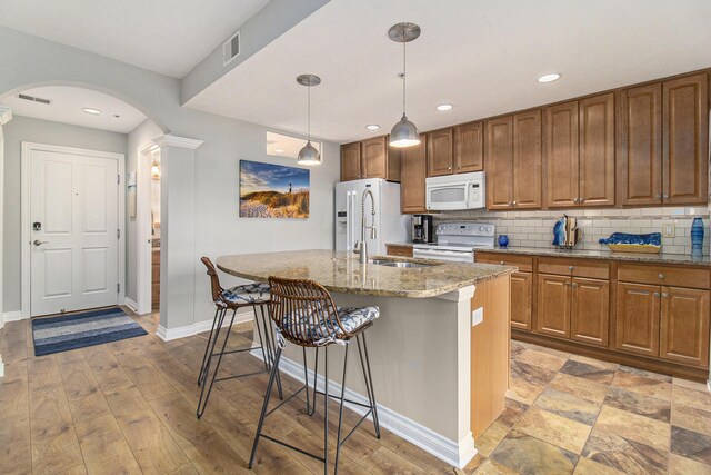 401 W Ludington Ave Unit 208, Ludington, MI 49431 - kitchen featuring visible vents, backsplash, a kitchen bar, arched walkways, and white appliances
