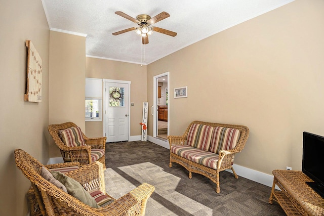 living area featuring ceiling fan, carpet floors, ornamental molding, baseboards, and a textured ceiling