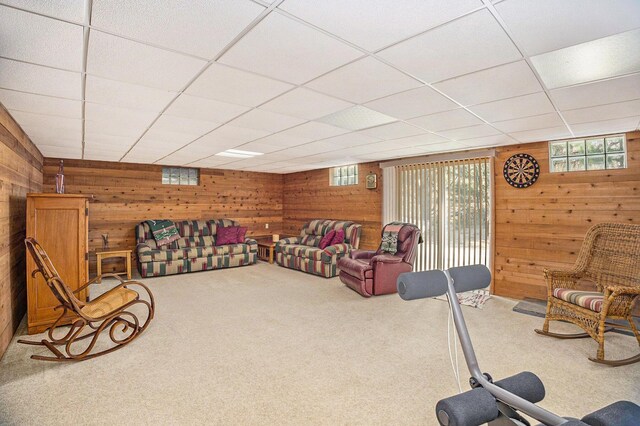 living room featuring wood walls, carpet, and a paneled ceiling