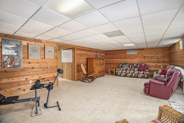 exercise room with wooden walls, carpet flooring, and a paneled ceiling