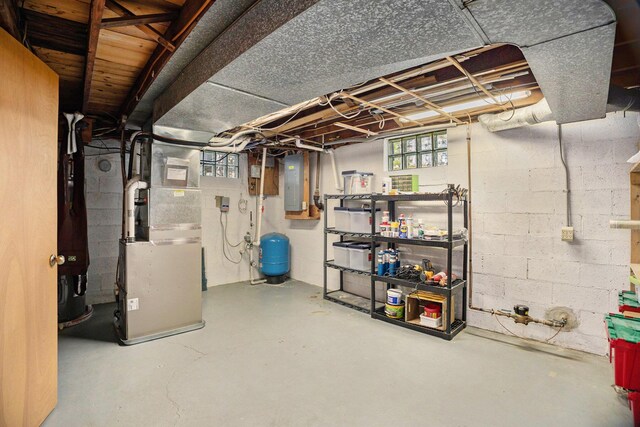 basement with electric panel, a water pressure tank, and heating unit