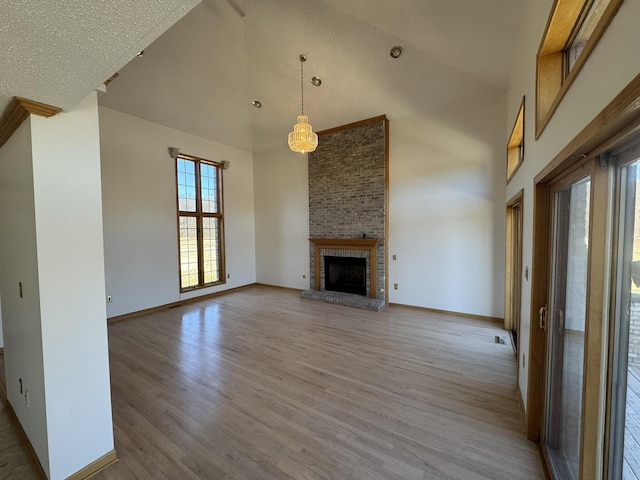 unfurnished living room with baseboards, high vaulted ceiling, wood finished floors, and a fireplace