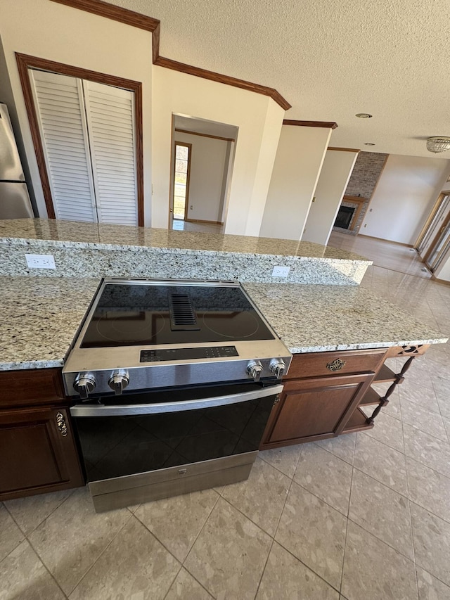 kitchen featuring crown molding, a textured ceiling, light tile patterned flooring, and light stone countertops