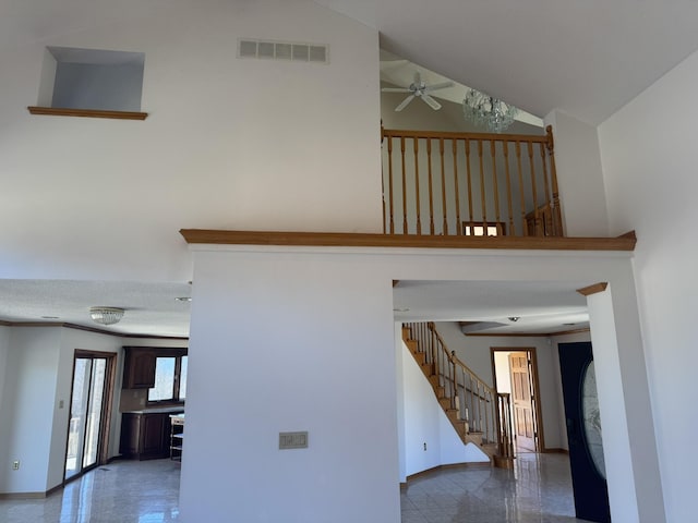 stairs with a ceiling fan, high vaulted ceiling, visible vents, and baseboards