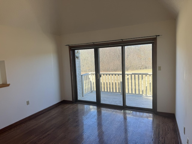 spare room with baseboards, visible vents, and dark wood-style floors