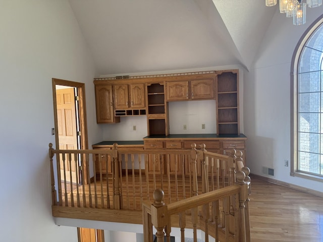interior space with visible vents, open shelves, baseboards, light wood-type flooring, and vaulted ceiling