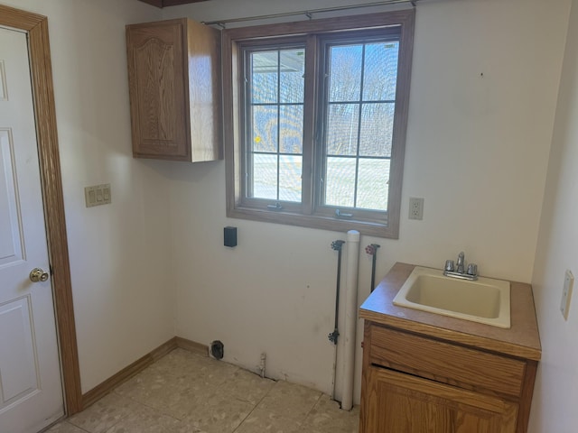 washroom featuring a sink, baseboards, cabinet space, and a wealth of natural light