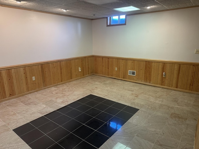 interior space with wooden walls, a wainscoted wall, and visible vents