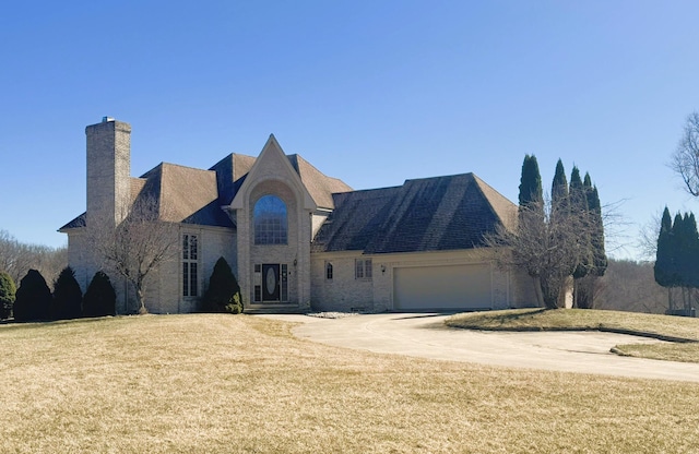 view of front of home featuring an attached garage, a chimney, concrete driveway, and a front lawn