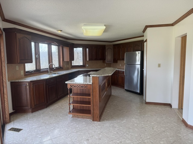 kitchen with crown molding, open shelves, freestanding refrigerator, a kitchen island, and a sink