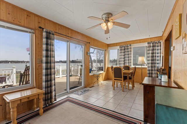 1169 Shady Shores Dr, Niles, MI 49120 - dining room with light tile patterned floors, a ceiling fan, a water view, and wood walls