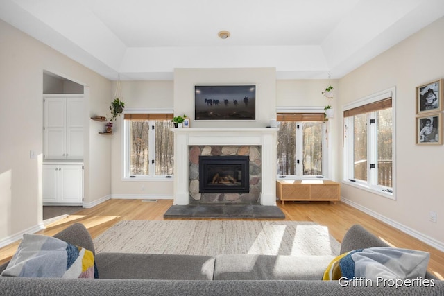 7834 Strawberry Ln NE, Belmont, MI 49306 - living area featuring a tray ceiling, wood finished floors, a fireplace, and baseboards