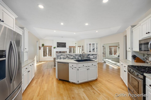 7834 Strawberry Ln NE, Belmont, MI 49306 - kitchen featuring light wood finished floors, open floor plan, appliances with stainless steel finishes, white cabinets, and a sink
