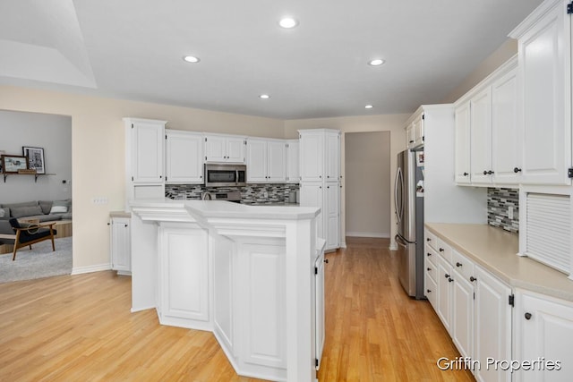 7834 Strawberry Ln NE, Belmont, MI 49306 - kitchen featuring light wood-style flooring, a kitchen island, white cabinetry, appliances with stainless steel finishes, and light countertops