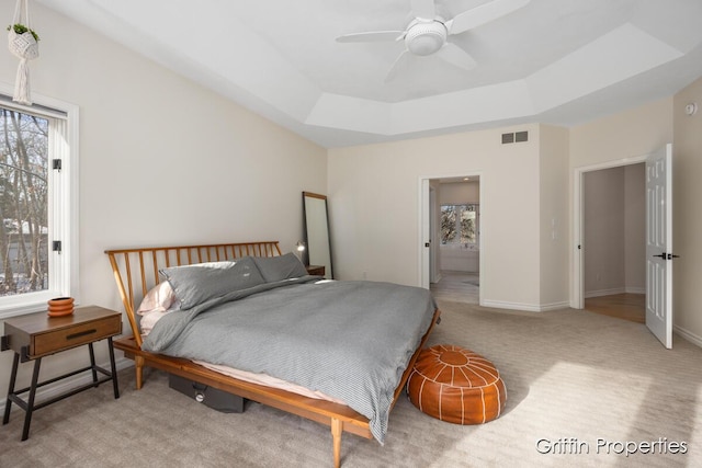 7834 Strawberry Ln NE, Belmont, MI 49306 - carpeted bedroom with a ceiling fan, baseboards, visible vents, a tray ceiling, and ensuite bath
