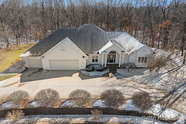 7834 Strawberry Ln NE, Belmont, MI 49306 - view of front of house with stucco siding, an attached garage, a shingled roof, and driveway