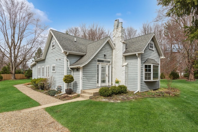 exterior space featuring a lawn, a chimney, a shingled roof, and fence