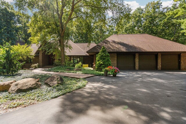 4923 Hickory Hill Rd, Ann Arbor, MI 48105 - view of front of home with aphalt driveway, an attached garage, brick siding, and roof with shingles