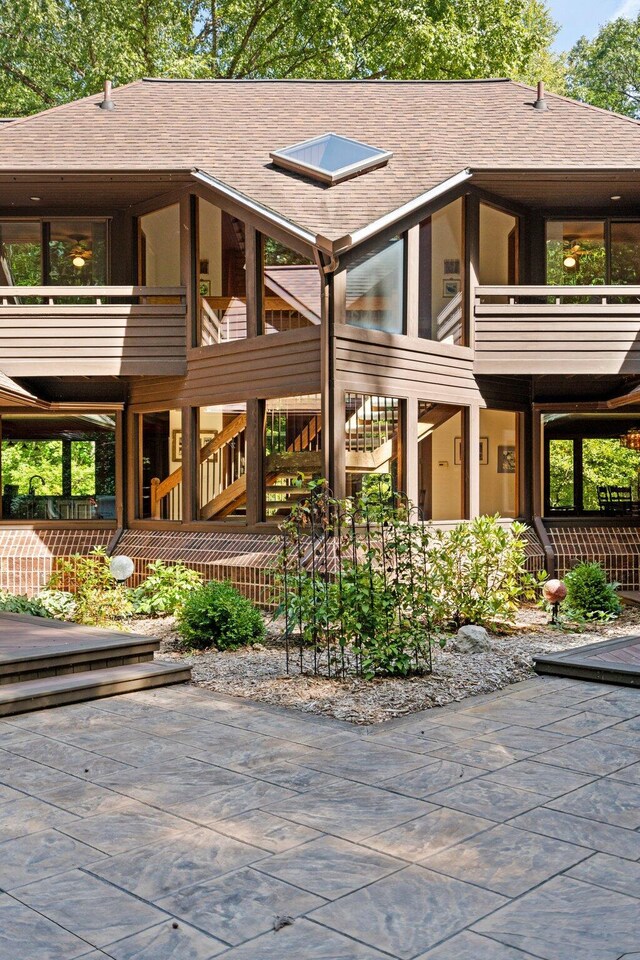 4923 Hickory Hill Rd, Ann Arbor, MI 48105 - rear view of house featuring a balcony, stairway, roof with shingles, and a patio area