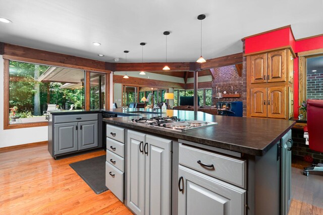4923 Hickory Hill Rd, Ann Arbor, MI 48105 - kitchen featuring stainless steel cooktop, light wood-type flooring, gray cabinetry, a kitchen island, and dark countertops