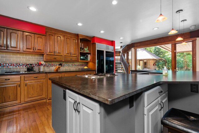 4923 Hickory Hill Rd, Ann Arbor, MI 48105 - kitchen featuring stainless steel gas stovetop, decorative backsplash, dark countertops, a sink, and refrigerator with glass door