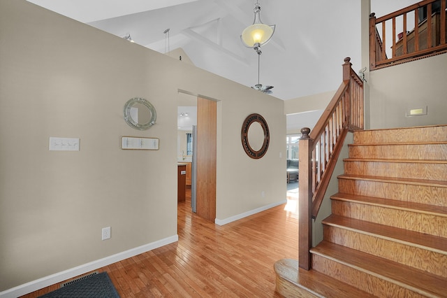 stairs featuring high vaulted ceiling, baseboards, and wood finished floors